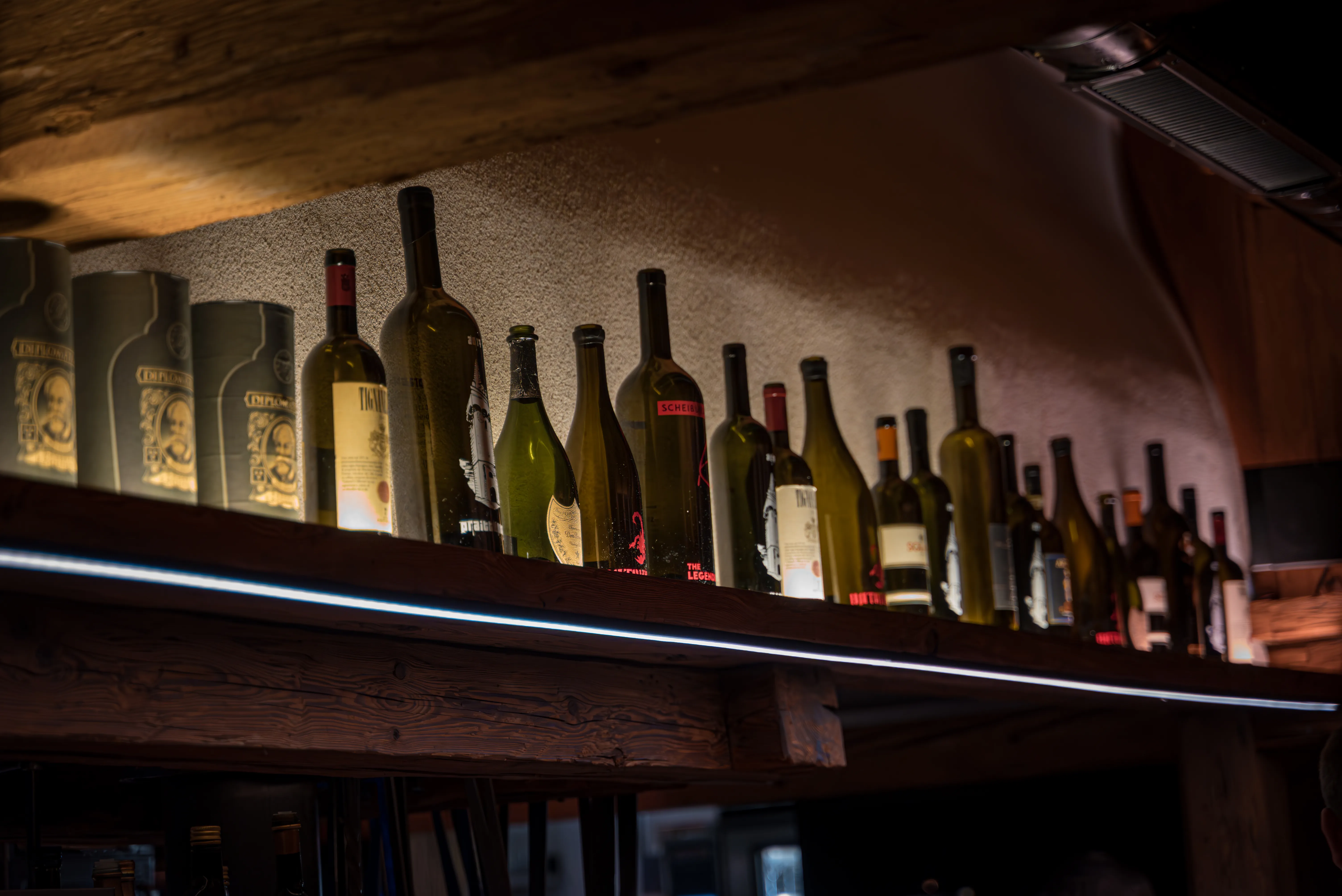 Beleuchtetes Weinregal in der urigen Almhütte – Wein und Kulinarik auf der Stöttlalm